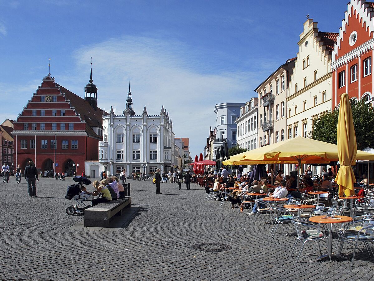 Ein Blick über den Greifswalder Markt. Es sind das Rathaus und die historische Apotheke zu sehen. 