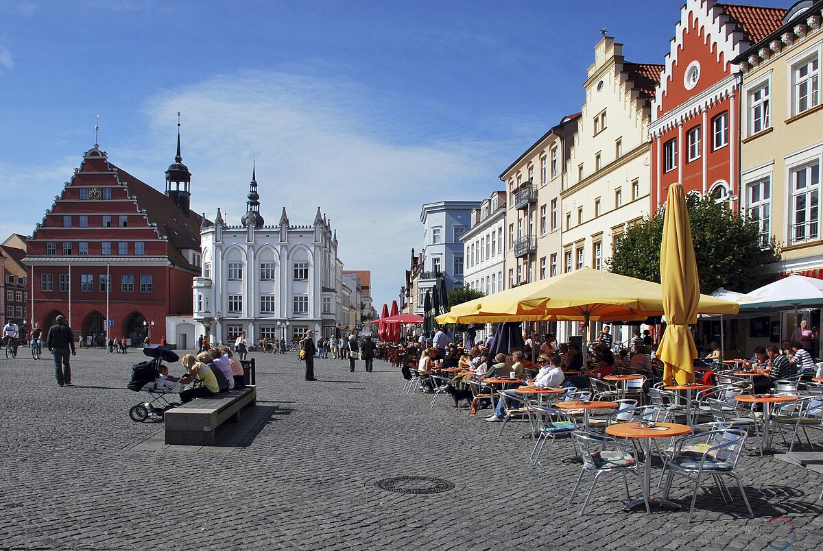 Ein Blick über den Greifswalder Markt. Es sind das Rathaus und die historische Apotheke zu sehen. 